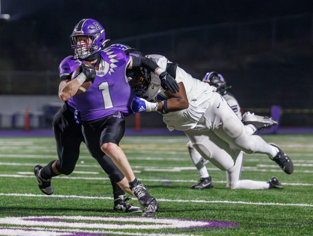 Anacortes' Luca Moore fights for yards as a Foster defender grabs his jersey.