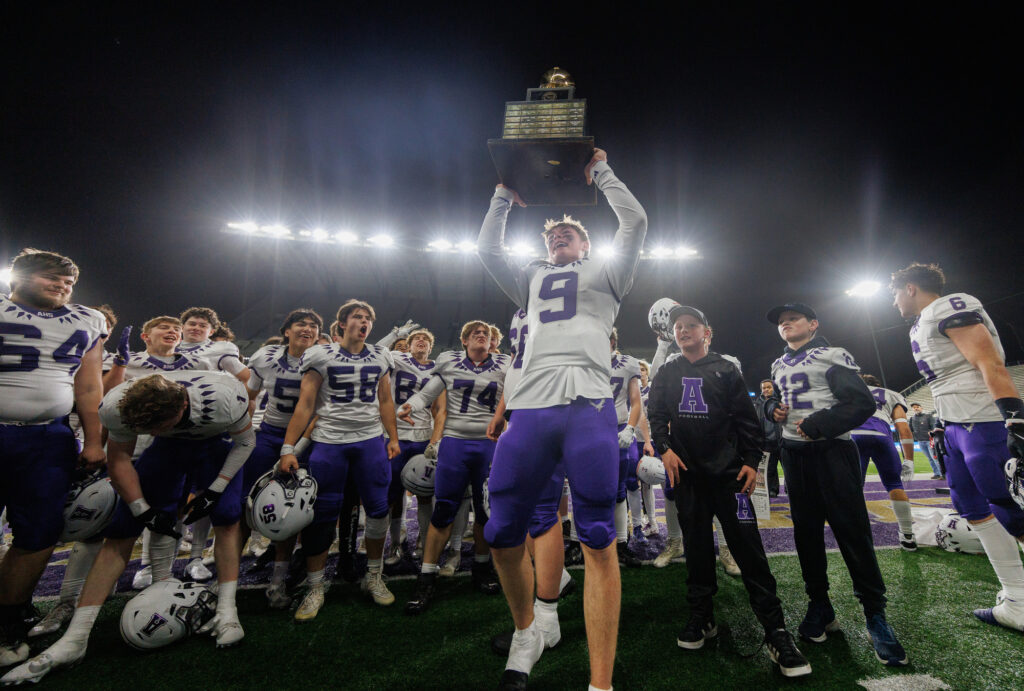 Anacortes quarterback Ryan Harrington holds up the 2A state championship trophy Saturday, Dec. 7 after beating Tumwater for the second straight season, 20-10, at Husky Stadium in Seattle.