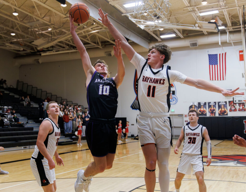 Anacortes’ Jake Andrew makes the layup under pressure from Bellingham’s Joe Harward Dec. 19.