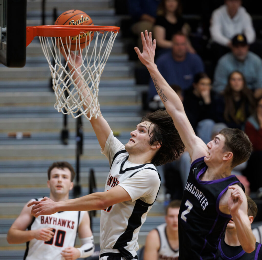 Bellingham’s Kincade Vanhouten passes Anacortes’ Ty Swapp for the basket.