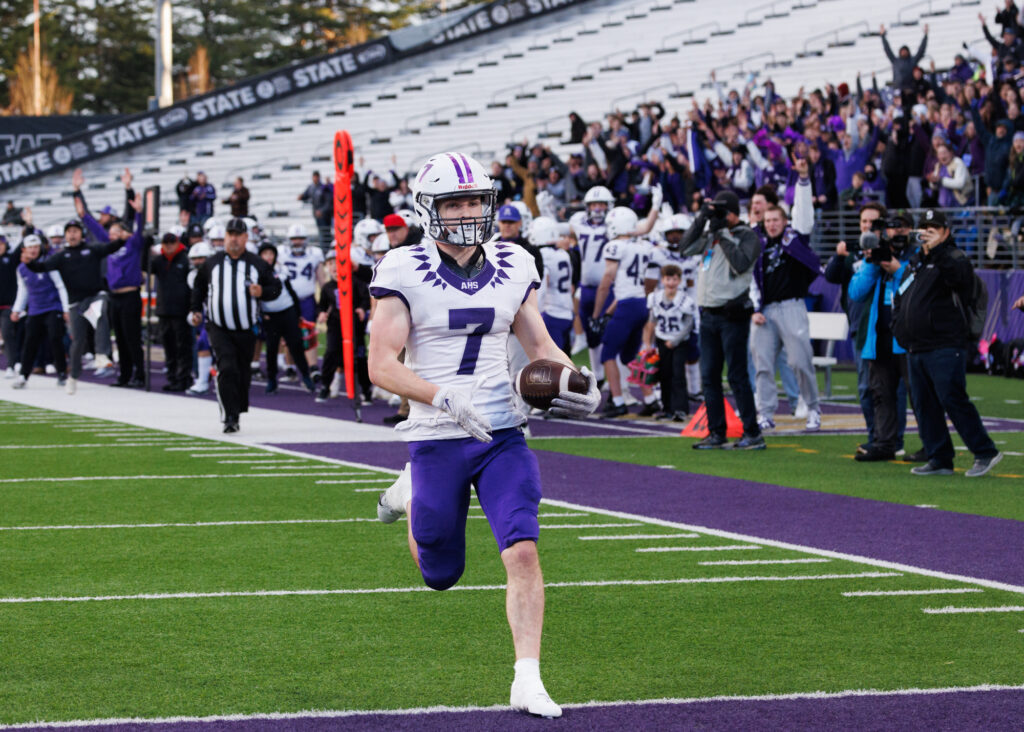 Fans and teammates hold up their arms as Anacortes senior Rylin Lang runs in for a 22-yard touchdown.