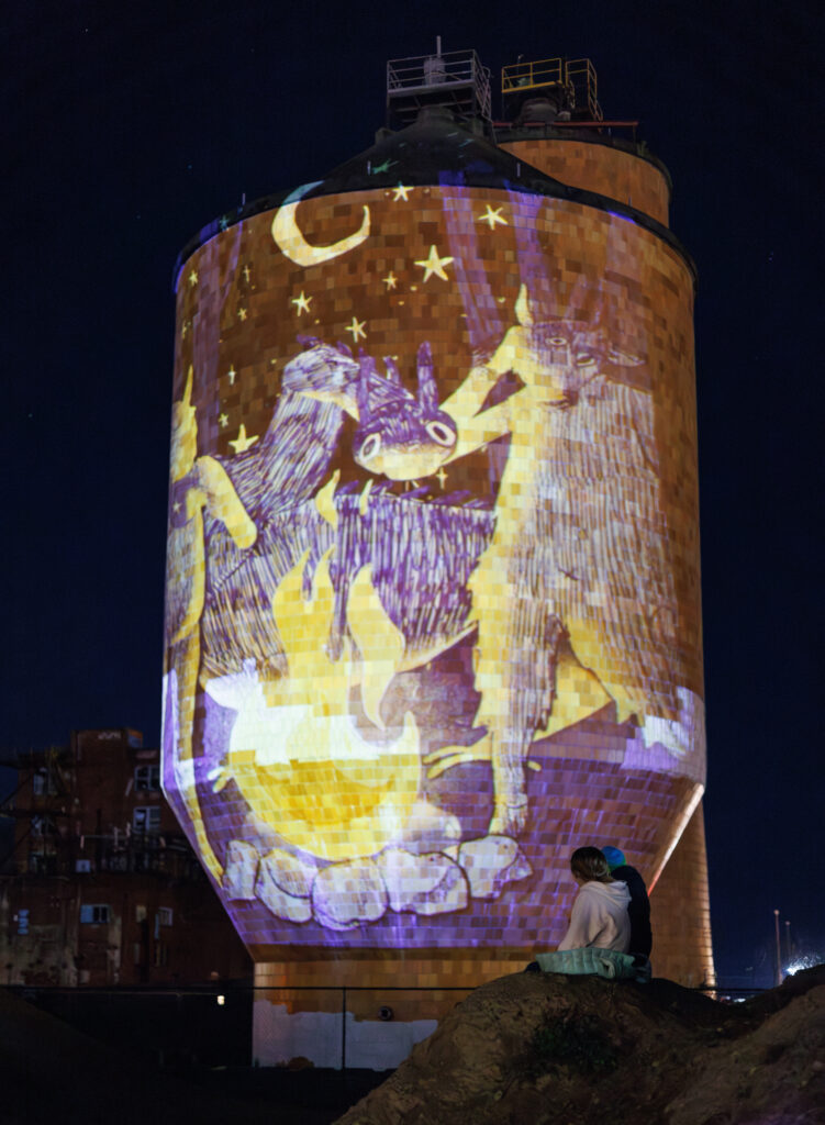 Children watch folk stories projected onto the tile tanks.