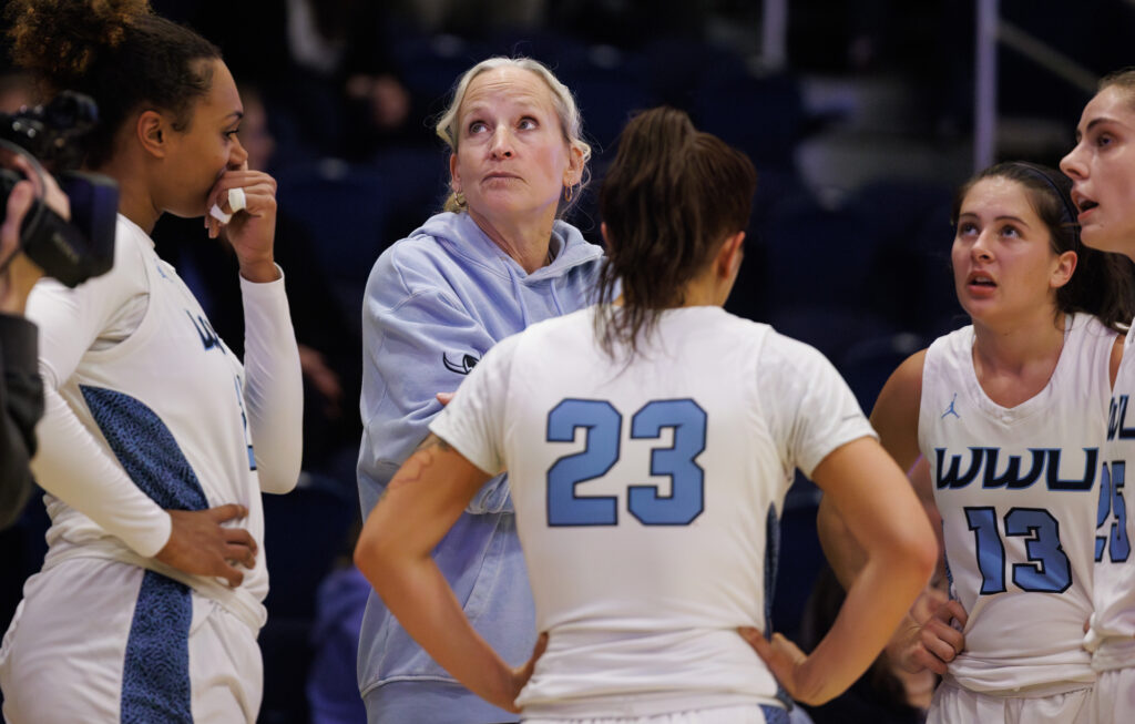 Western head coach Carmen Dolfo looks up at the scoreboard in the fourth quarter as her team trails Northwest Nazarene by 10 points.