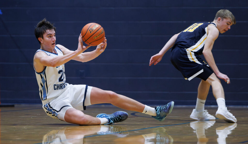 Lynden Christian’s Luke VanKooten throws a pass to a teammate from the court floor during a game against Burlington-Edison on Jan. 3.