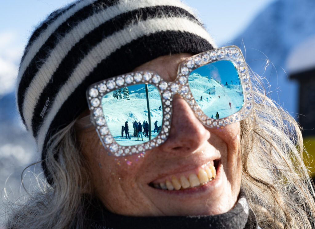 Mt. Baker Ski Area CEO Gwyn Howat dons large, sparkly sunglasses that reflect the mountain and racers.