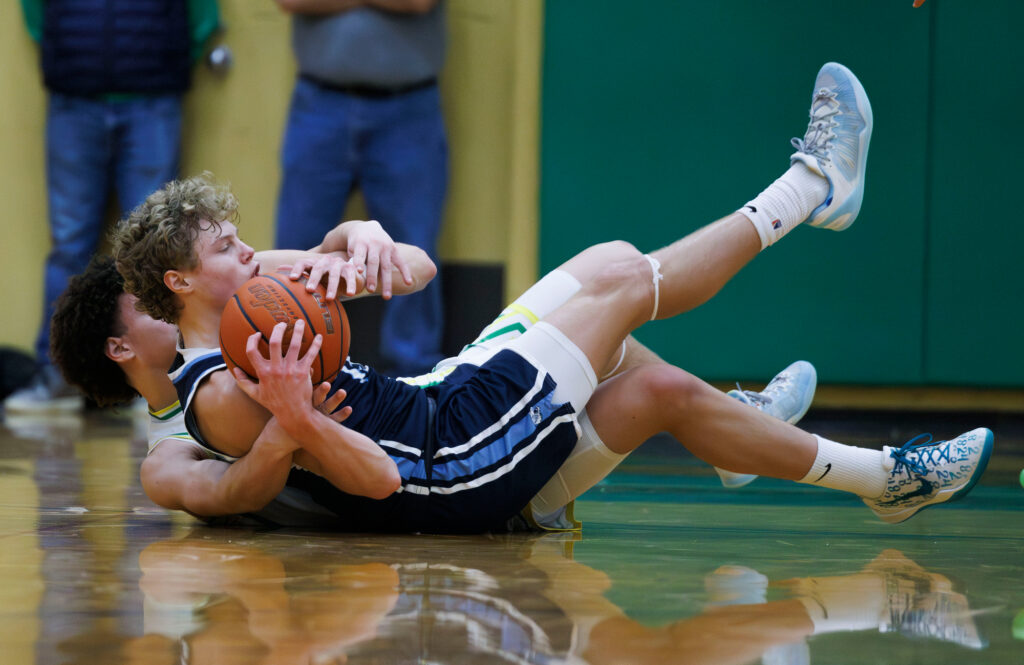 Lynden Christian’s Gannon Dykstra grabs a loose ball as Lynden’s Jayden Navarre wraps him up.