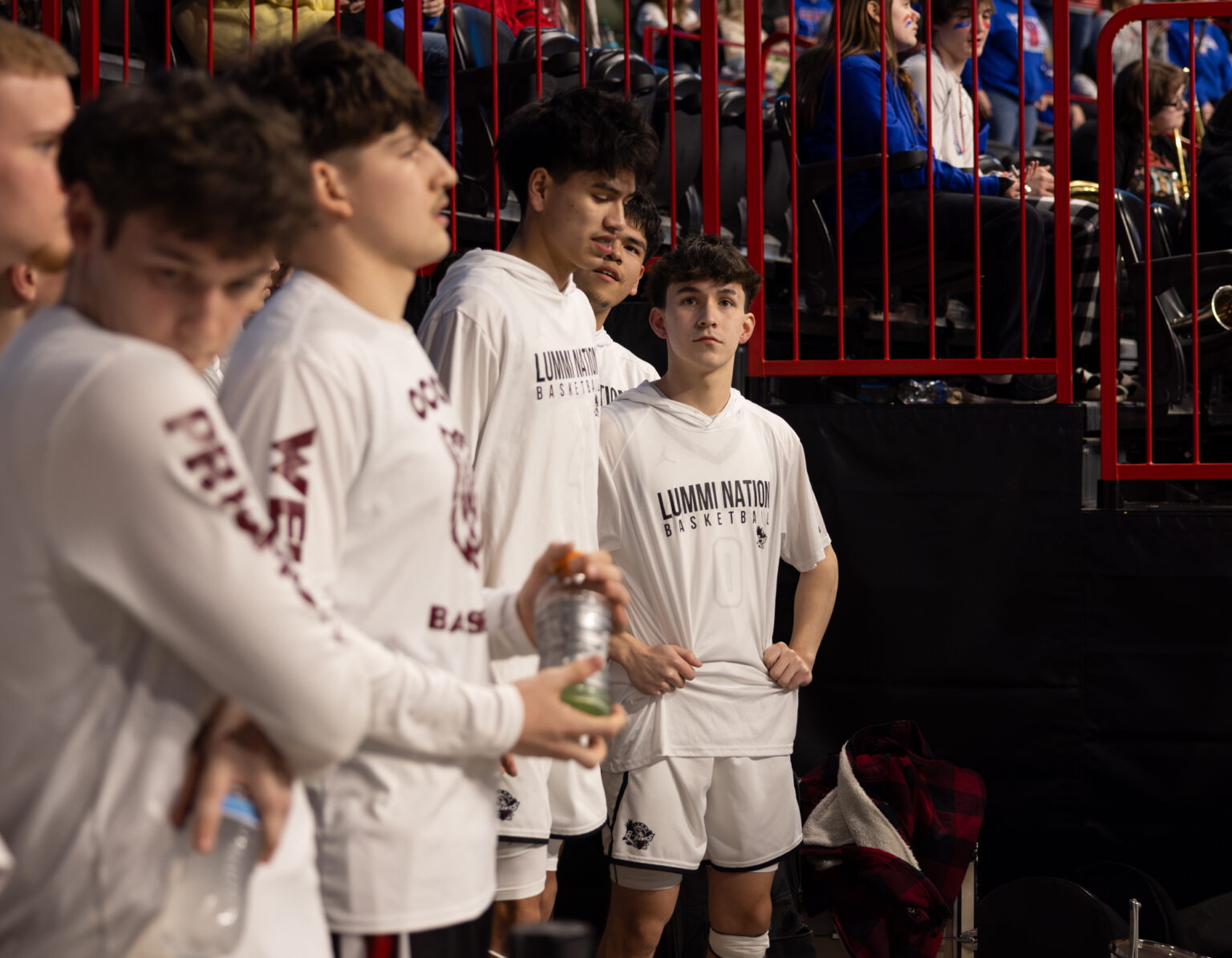 Lummi Nation and Ocosta players stand next to each other while they wait for the game before theirs to end.