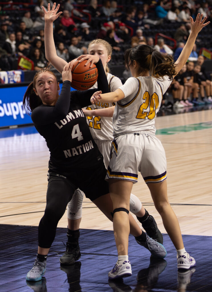 Lummi junior guard Kashlyn Mack rips through two defenders on the way to the hoop.