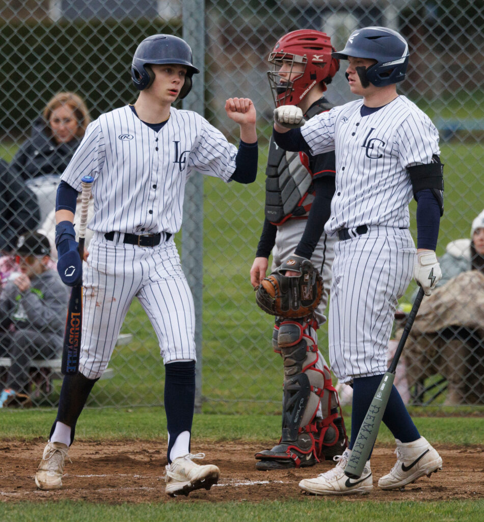 Lynden Christian’s Jaxon Huleatt and Austin Engels bump fists after Huleatt scores a run.