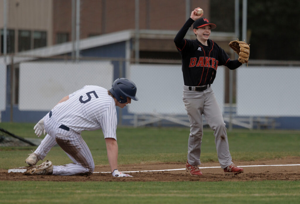 Mount Baker’s Brad Strom holds up the ball smiling after his second tag out at third base.